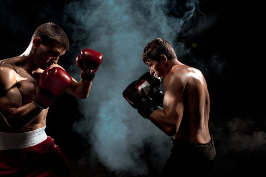 Two professional boxer boxing on black smoky background,