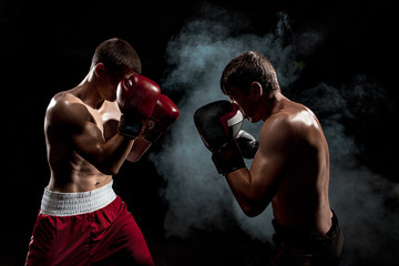 Fototapeta na wymiar Two professional boxer boxing on black smoky background,