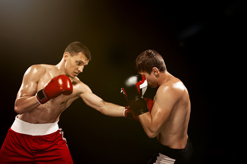 Naklejka na ściany i meble Two professional boxer boxing on black background,