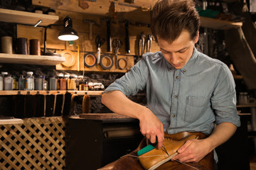 Concentrated shoemaker in workshop making shoes