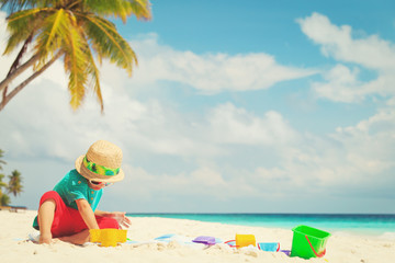 Fototapeta na wymiar little boy play with sand and toys on beach