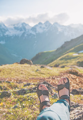 Fototapeta premium Legs of traveler sitting on top of mountain. Travel concept