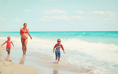 Naklejka premium happy pregnant mother with kids play on beach