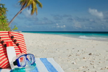 bag, diving mask and suncream on beach
