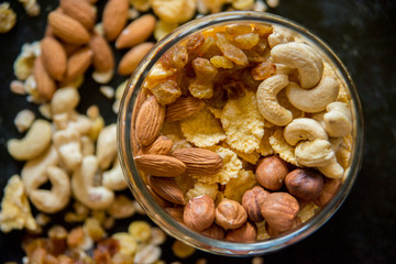 Healthy breakfast. Fresh granola, muesli with berries, honey in a glass jar on a black slate background.