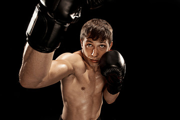 Male boxer boxing in punching bag with dramatic edgy lighting in a dark studio