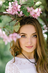 Naklejka premium Young beautiful girl walking in a beautiful park among the flowering trees