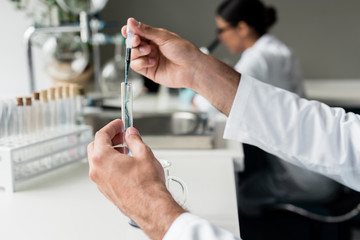 Cropped shot of scientist holding test tube with reagent while making experiment in lab