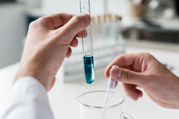 Close-up partial view of scientist making experiment in chemical lab