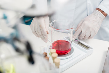 Cropped shot of scientist making experiment with reagent in flask and electronic scales