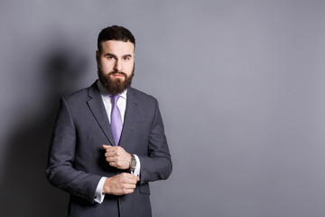 Bearded man in suit adjusting sleeves copy space