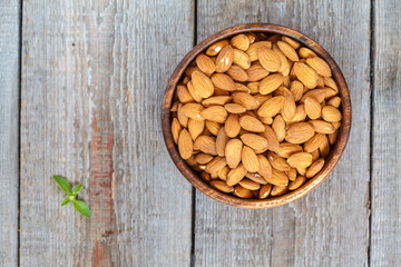 Raw almond nut in a wooden bowl. Vegetable protein, dietary snack, top view.