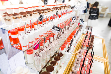 Delicious and tasty dessert table with cupcakes shots at reception closeup