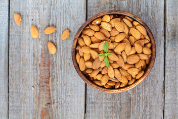 Raw almond nut in a wooden bowl. Vegetable protein, dietary snack, top view.