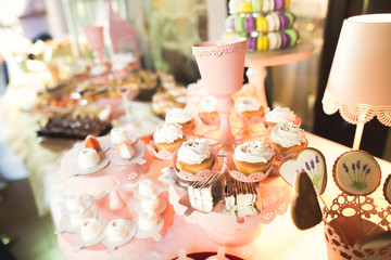 Delicious sweets on wedding candy buffet with desserts, cupcakes