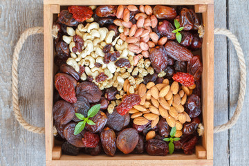 Different types of nuts and dried fruits in a wooden box.  Healthy dietary snack, dried fruit, nuts, top view.
