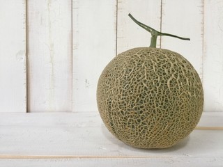 closeup green cantaloupe head at the right side of white cream timber board,in abstract art design,blurry light tone