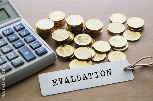 Evaluation Word On Tag Label With Calculator And Gold Coins Evaluation Word On Tag Label With Calculator And Gold Coins Financial Concept