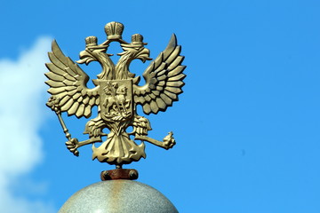 Fototapeta na wymiar Coat of arms of Russia in bronze in the form of a two-headed eagle against the blue sky.