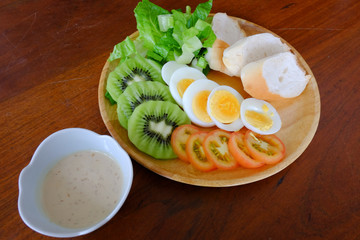 liced egg salad serve with vegetable, kiwi, tomato, crispy bread, and separated sesame dressing (45 degree angle view )