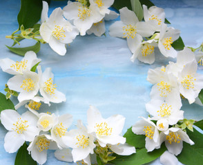 Beautiful delicate frame of white jasmine flowers on blue with gray watercolor background, floral texture