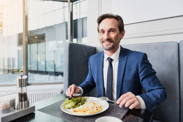 Joyful male manager having lunch in cafe