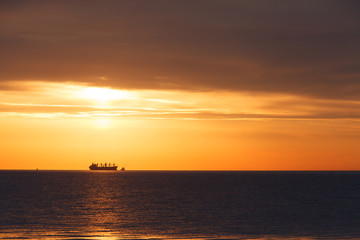Fototapeta na wymiar Dawn at the sea. In the distance a ship can be seen.
