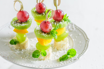 Homemade skewers with fruits and mint on white table