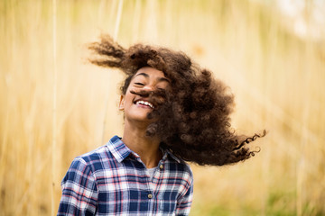 African american girl in checked shirt outdoors in field.