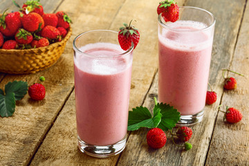Milkshake made of fresh ripe strawberry on a rustic wooden table. Healthy fruit drink for healthy breakfast.