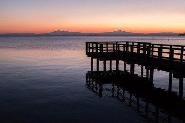 Naklejka na ściany i meble A pier on a lake at dusk, with beautiful soft and warm colors