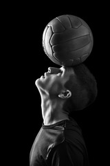  Caucasian young boy balances a classic leather soccer ball on his forehead. sport and skill...