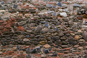 Medieval wall built of stone and bricks, background texture