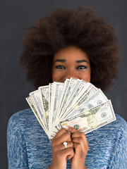 black woman holding money on gray background