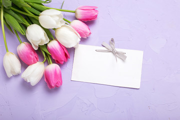 Obraz na płótnie Canvas Empty tag and tulips flowers on violet textured background.