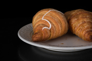 Cinnamon crescents croissant on white plate on black background