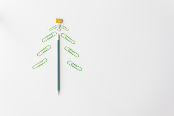 pencil and paper clip lay like a Christmas tree on white background