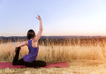Fototapeta na wymiar Young woman in yoga pose outdoors at sunset 