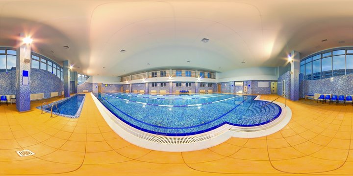 Big indoor swimming pool with blue water at fitness centre with yellow floor tiles full 360 degree panorama in equirectangular spherical projection