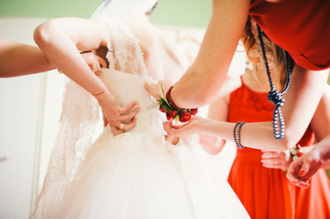Obraz na płótnie Canvas hand lace up corset on bride's delicate waist, colorfull
