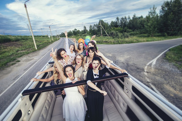 Young beautiful happy women celebrate bachelorette party in a convertible limousine