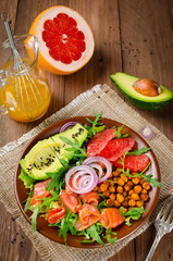 Healthy salad bowl with salmon, grapefruit, spicy chickpeas, avocado, red onion and arugula
