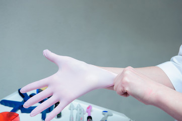 A young female doctor preparing herself for working, putting on protective gloves.