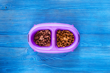 Obraz na płótnie Canvas Animal feed in bowl on blue table background top view copyspace