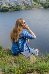 Young girl in blue clothes, wearing sunglasses talking on the phone in summer on the street