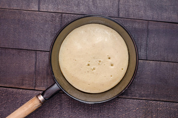 Raw pancake in a frying pan on a dark background - 163823829