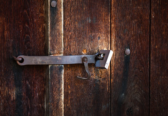 Old latch with padlock on wood doors.