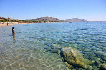 Piękny widok czystego dna morskiego, ludzie w wodzie i na plaży wyspy Rodos. - obrazy, fototapety, plakaty