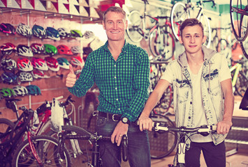 Obraz na płótnie Canvas Father with teenager trying new bicycle