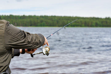 Man fishing with spinning rod in a lake.